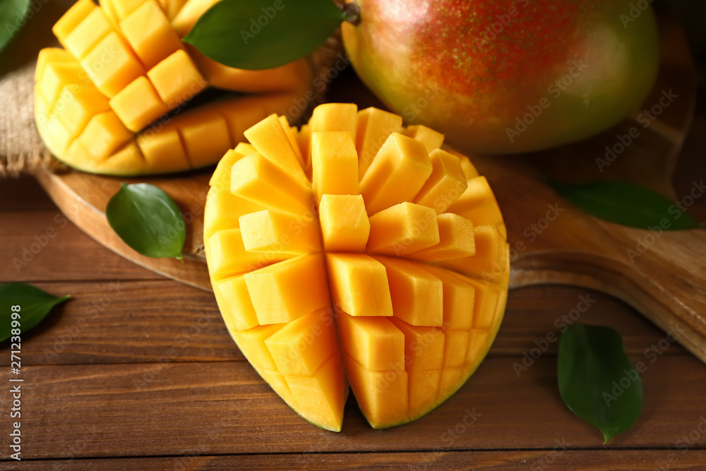 Board with tasty fresh mango on wooden table Board with tasty fresh mango on wooden table