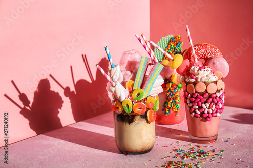 Different delicious freak shakes on color background photo