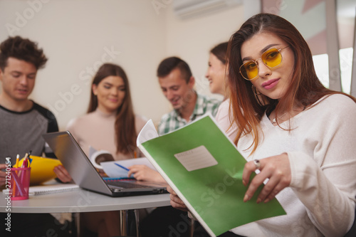 Confidence, success concept. Attractive young female college studentsmiling to the camera, while preparing for exams with her classmates, copy space photo