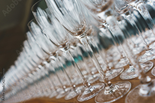 Several rows clear, clean glasses for wine and champagne on counter prepared for drinks.