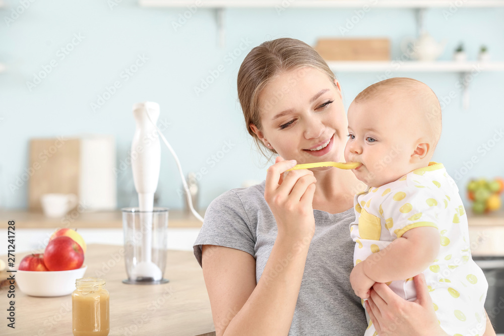 Mother feeding her little baby in kitchen at home Mother feeding her little baby in kitchen at home