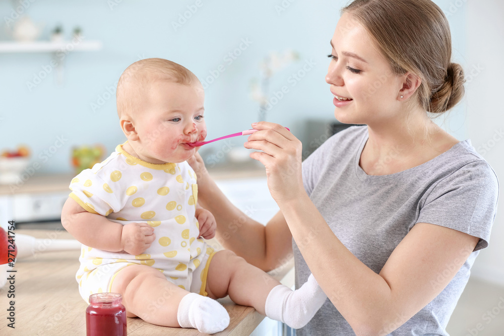 Mother feeding her little baby in kitchen at home Mother feeding her little baby in kitchen at home