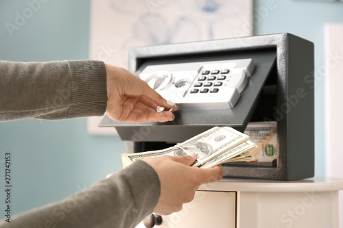 Cuadro en lienzo Woman putting money in safe at home
