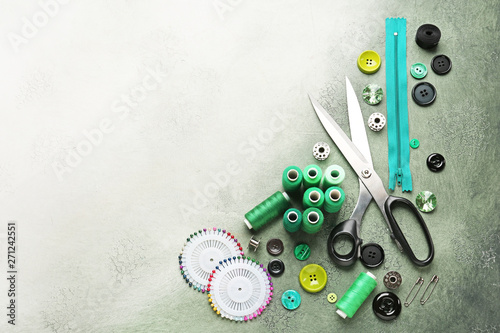 Set of sewing threads and accessories on color background