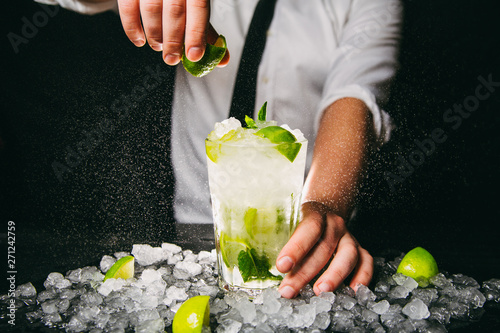 Фотография Close-up of professional barman squeezing lime making Mojito cocktail
