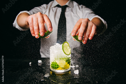 Foto Professional bartender squeezing lime making Caipirinha cocktail