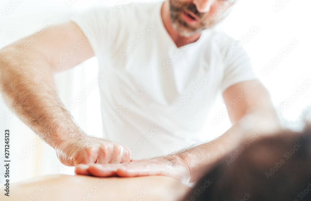 Bearded Masseur man doing massage manipulations on the Scapula area