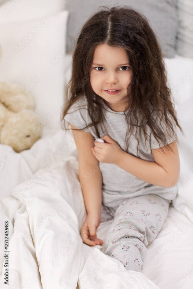 Sick little child girl lying in bed with thermometer. Cold flu season