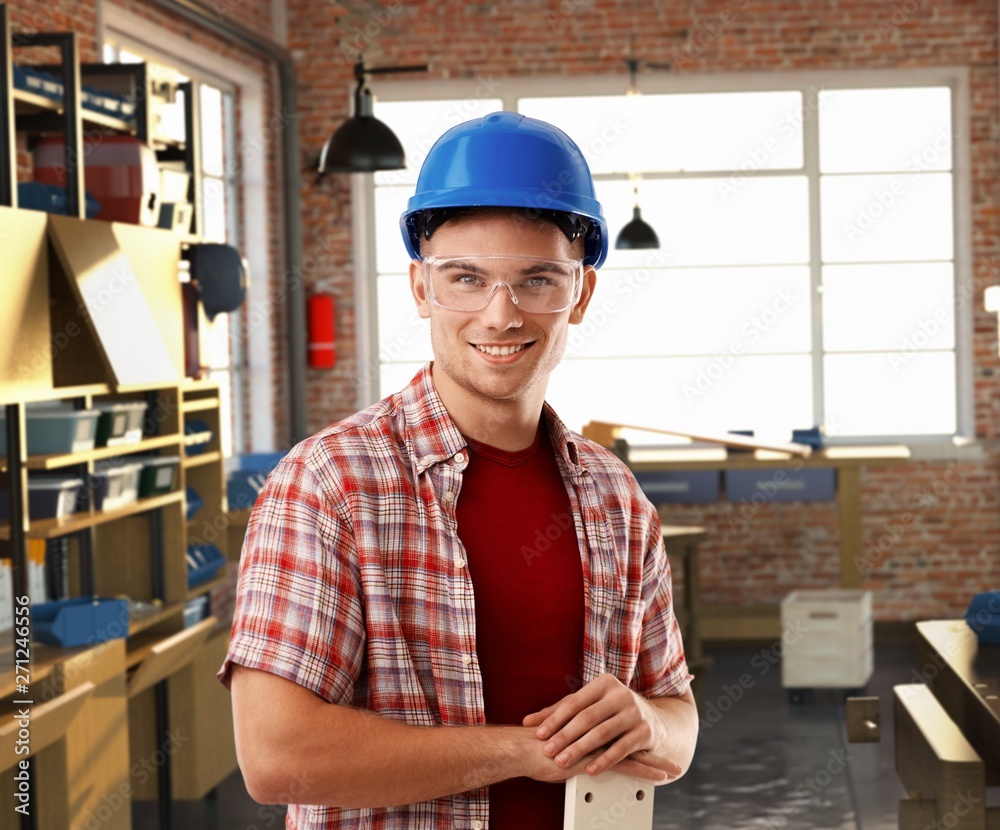 Happy rookie worker with hardhat at workshop Happy rookie worker with hardhat at workshop