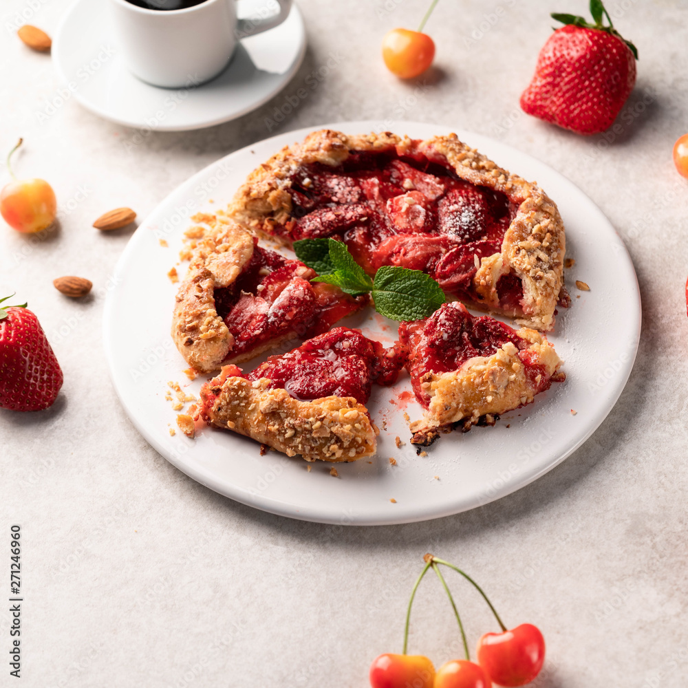 homemade strawberry galleta (biscuit) on a white plate on a light marble backdrop, strawberries and cherries as part of composition homemade strawberry galleta (biscuit) on a white plate on a light marble backdrop, strawberries and cherries as part of composition