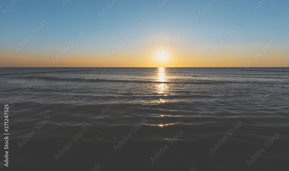 sunset over the horizon of the ocean with cloudless sky