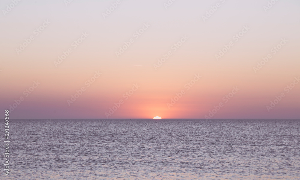 sunset over the horizon of the ocean with cloudless sky