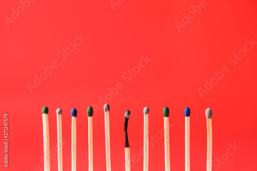 One burnt-out match among unburnt ones on color background. Concept of uniqueness