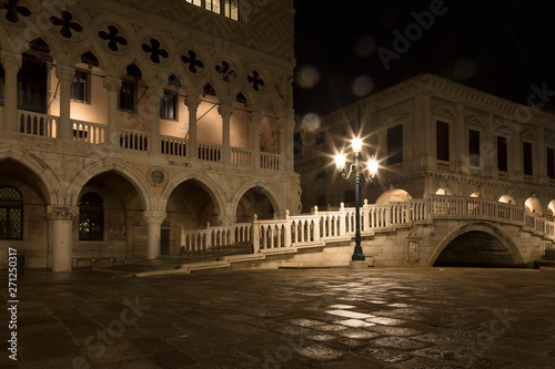 Bridge via the Palace channel, a lamp and a wall of Doges Palace at night during a rain, Venice