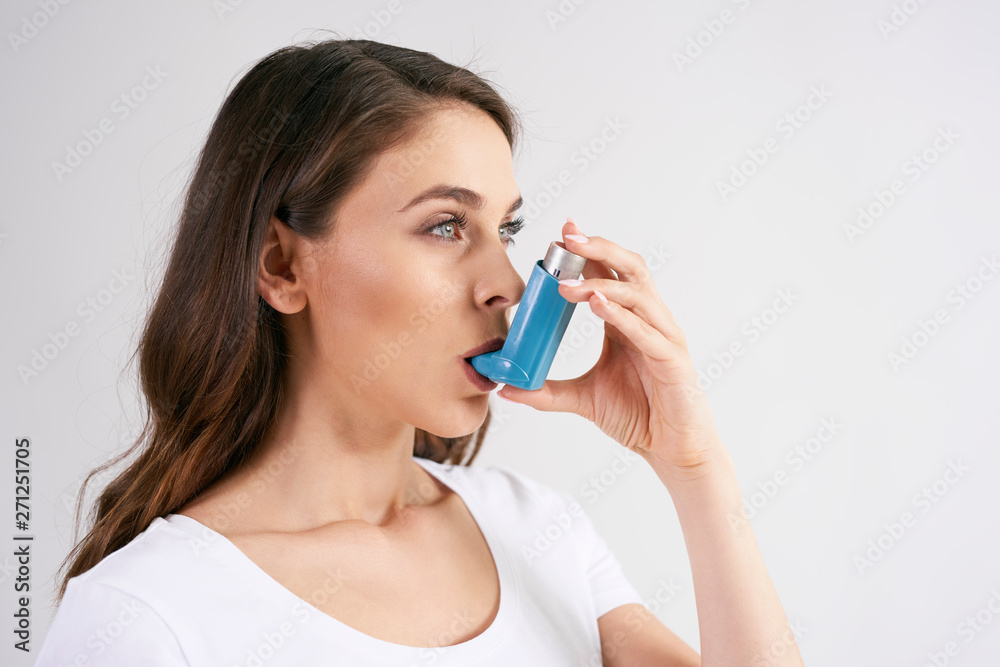 Asthmatic woman using an asthma inhaler during asthma attacks Asthmatic woman using an asthma inhaler during asthma attacks