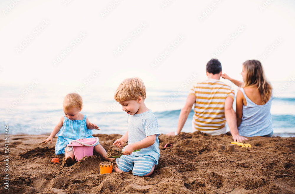 Toddler children with parents playing on sand beach on summer holiday. Toddler children with parents playing on sand beach on summer holiday.
