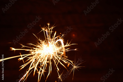 Holiday Bengal lights on the dark background. Burning sparkler  Happy New Year.