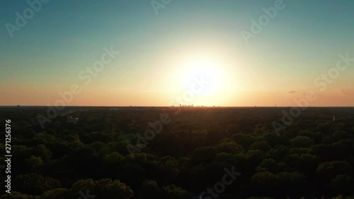 Aerial city sunset approaching downtown over trees