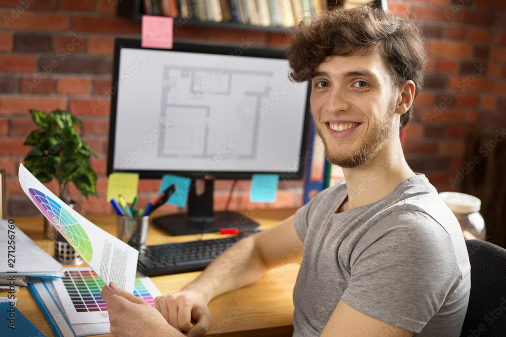 Fototapeta premium Young smiling man working at his workplace