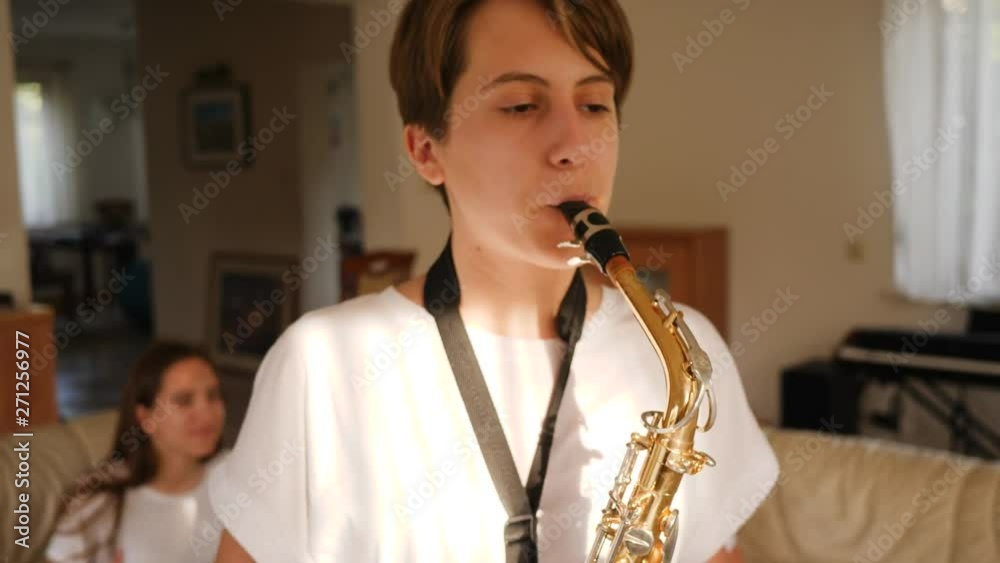 Amateur music band teenager triplet sisters play music at home using sax, drum and piano