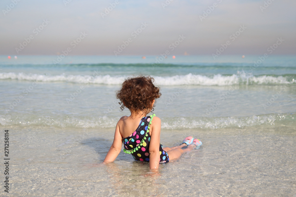 little adorable girl 2-3 years plays joyfully on the beach in sunset on holiday little adorable girl 2-3 years plays joyfully on the beach in sunset on holiday