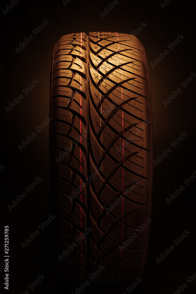 Brand new modern car tyre on a black background. Studio shot