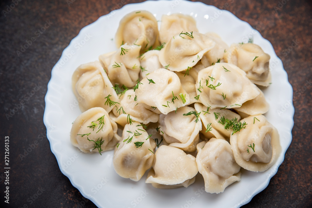 Meat dumplings - russian pelmeni, ravioli with meat on plate on a wooden background Meat dumplings - russian pelmeni, ravioli with meat on plate on a wooden background