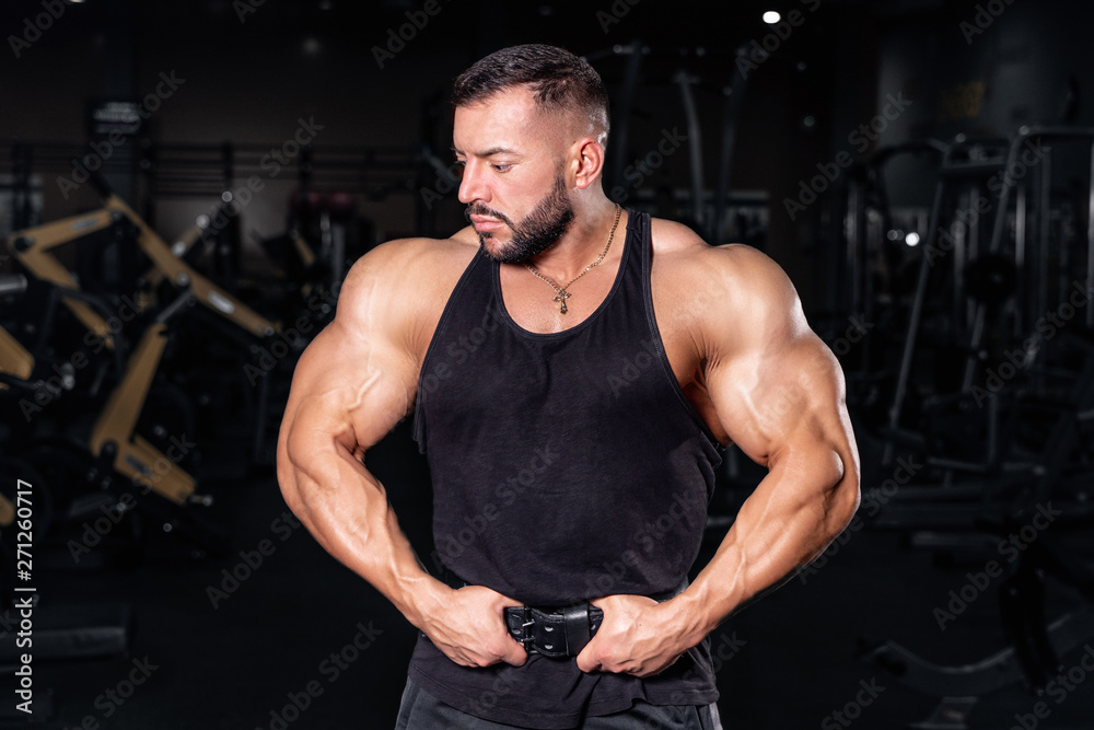  Bodybuilder in the gym. Sports photo shoot. Man's fitness. Training and exercises with dumbbells. Men's photo shoot in low key. Athletic build.