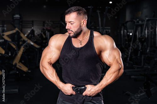  Bodybuilder in the gym. Sports photo shoot. Man s fitness. Training and exercises with dumbbells. Men s photo shoot in low key. Athletic build.