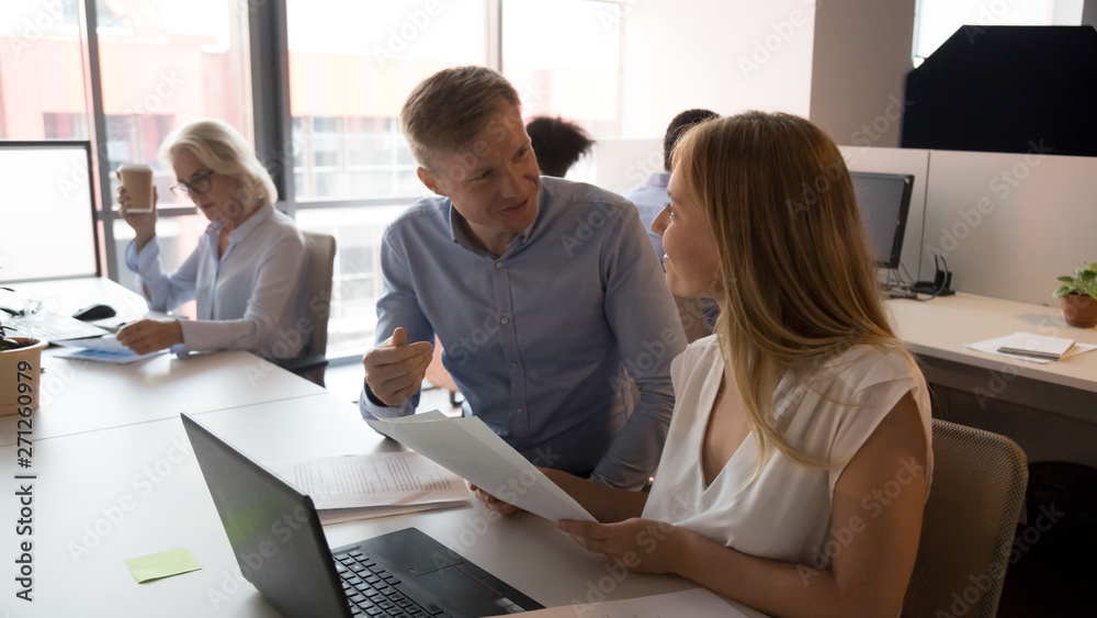 Confident businessman mentor helping female intern with paperwork Confident businessman mentor helping female intern with paperwork