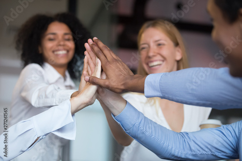 Close up diverse employees joining hand, giving high five
