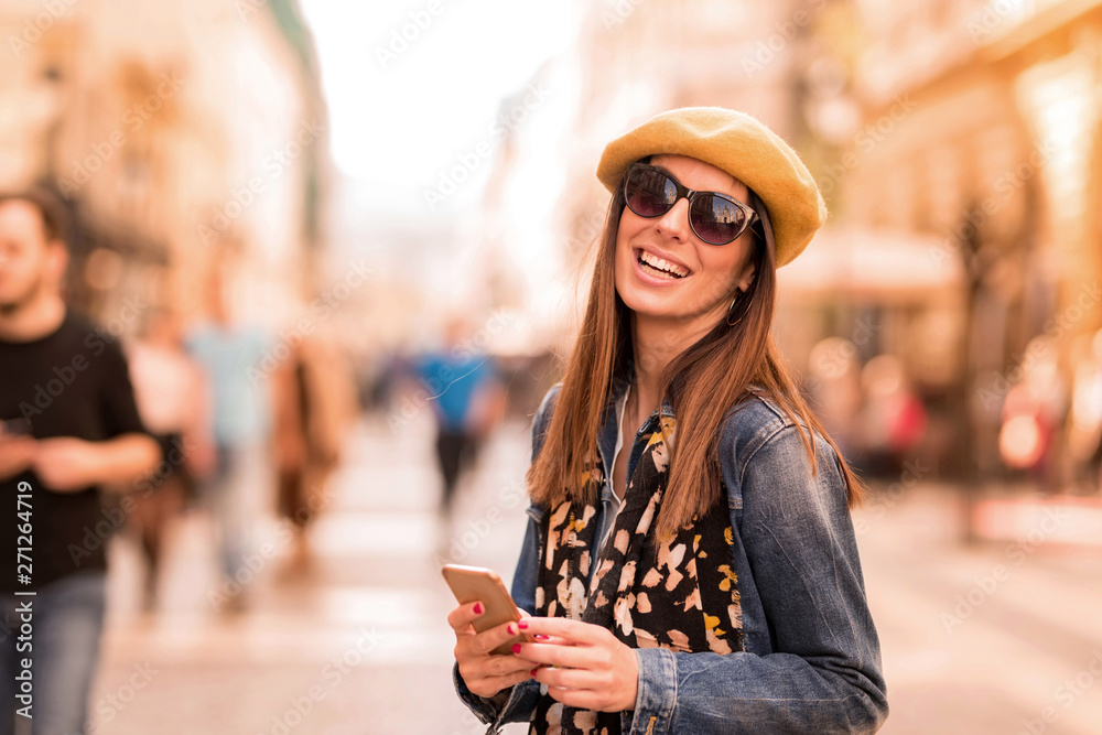 Obraz premium A woman using her smartphone in the pedestrian zone