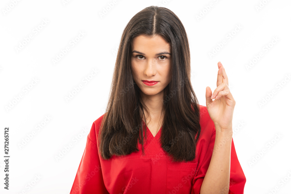 Portrait of beautiful young nurse wearing scrubs holding fingers crossed Portrait of beautiful young nurse wearing scrubs holding fingers crossed