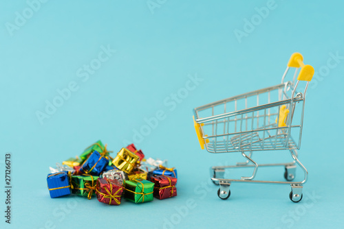 Christmas gifts in supermarket trolley on blue background . Online shopping concept - trolley cart full of presents. Black Friday and Ciber Mondey photo