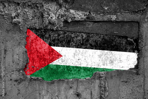The flag of Palestine on a dirty wooden surface, built into a concrete base, with scuffs and scratches. Loss or destruction conception.