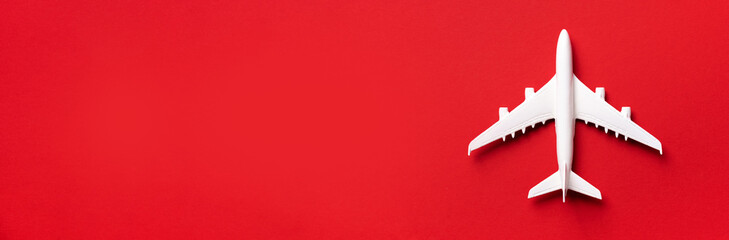 Travel, vacation concept. White model airplane on red color background with copy space. Top view. Flat lay. Minimal style design. Banner