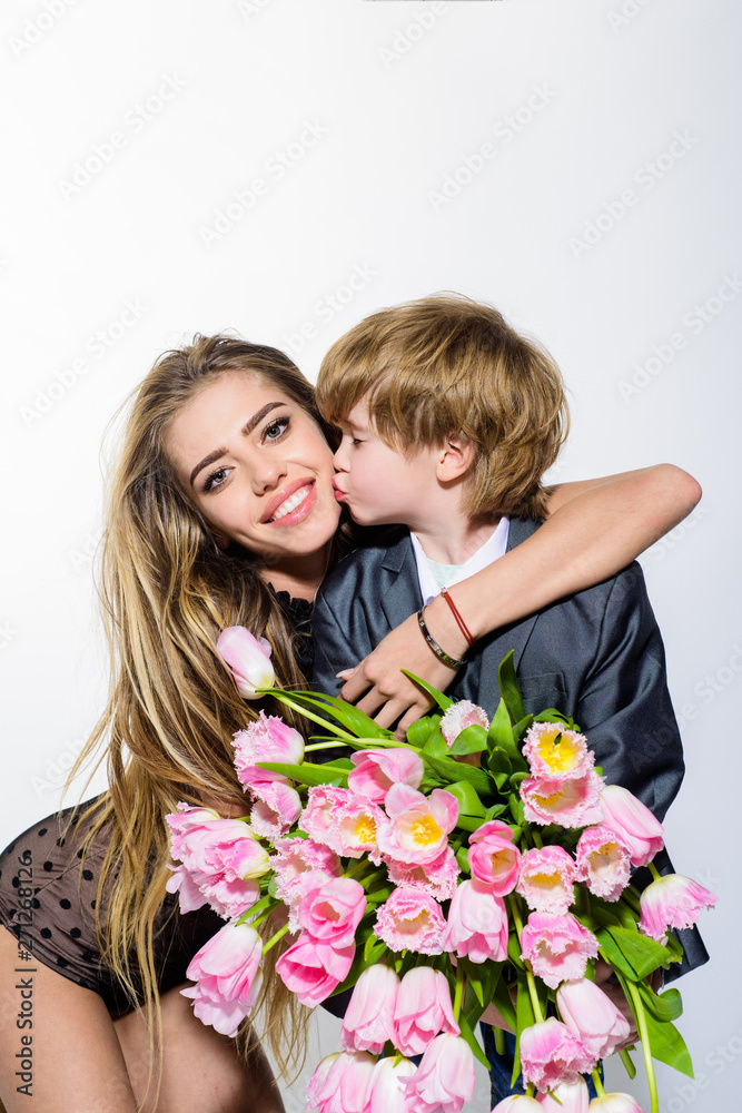 Holidays, love, happiness and people concept. Cute little gentleman giving bouquet of flowers to charming lady. Adorable small son greeting mother. Happy family. Mom and toddler kissing and hugging. Holidays, love, happiness and people concept. Cute little gentleman giving bouquet of flowers to charming lady. Adorable small son greeting mother. Happy family. Mom and toddler kissing and hugging.