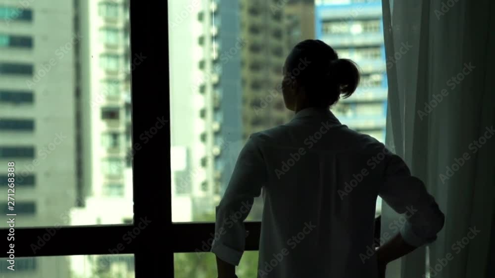Woman unveil curtain and admire view from window at home