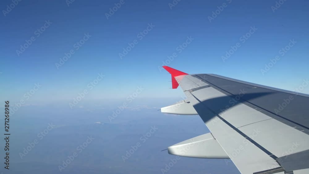 Wing of an airplane flying above the morning clouds. Aircraft wing in the sky, looking through the window Wing of an airplane flying above the morning clouds. Aircraft wing in the sky, looking through the window