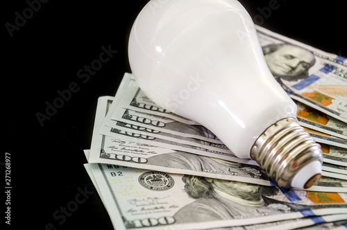 energy saving light bulb with dollars on a black background. Close-up.