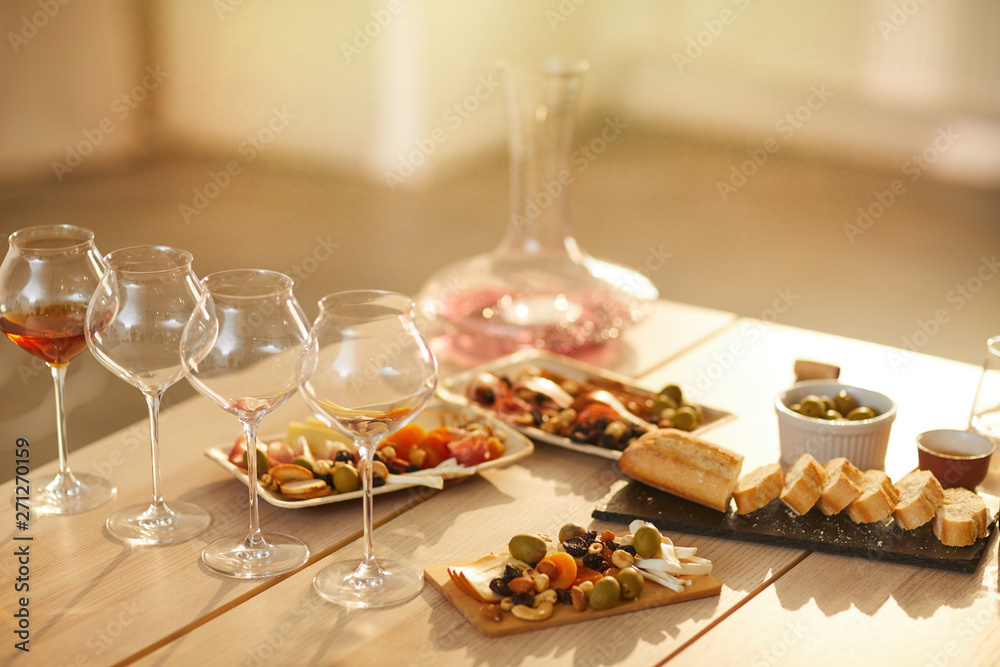 Background image of wine glasses on wooden table with rustic snacks set for wine tasting session in sunlight, copy space