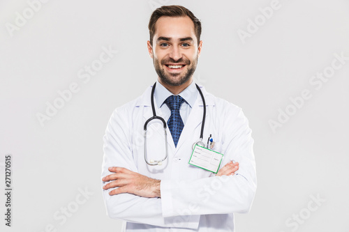 Portrait of brunette young medical doctor with stethoscope smiling at camera and standing wth arms crossed photo