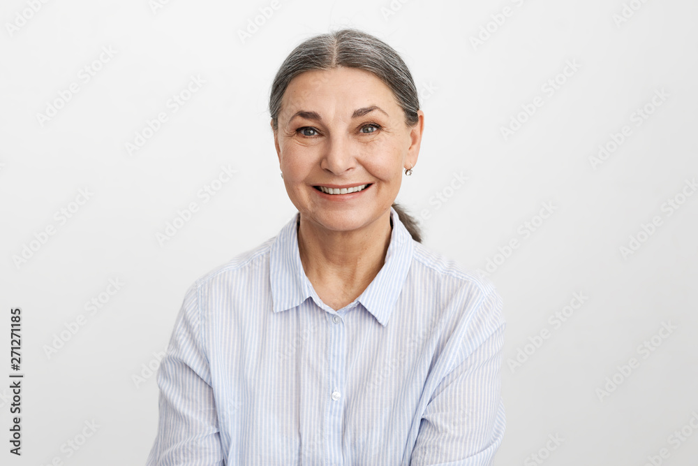 People, age, business and elegance. Attarctive cheerful gray haired mature businesswoman rejoicing at profitable contract, smiling happily. Senior female in blue shirt expressing positive emotions