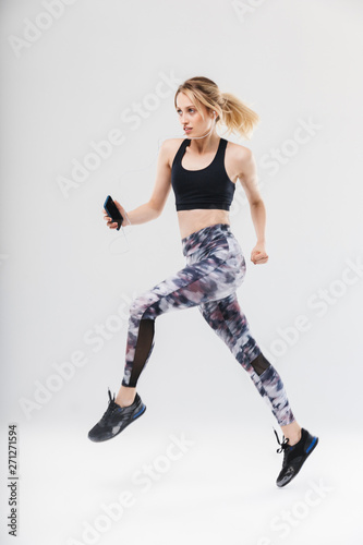 Image of caucasian blond woman 20s dressed in sportswear working out and listening to music with smartphone