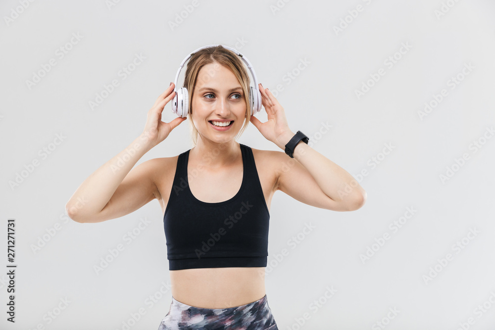 Image of lovely blond woman 20s dressed in sportswear listening to music with headphones during workout in gym Image of lovely blond woman 20s dressed in sportswear listening to music with headphones during workout in gym