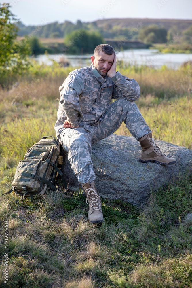 Soldier tying shoes. Soldier. Soldier in gear. The soldier sits and rests.	