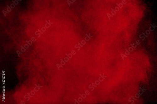 Red color powder explosion on black background. Freeze motion of red dust particles splash. photo
