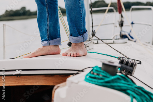 Bare feet stand on deck of yacht