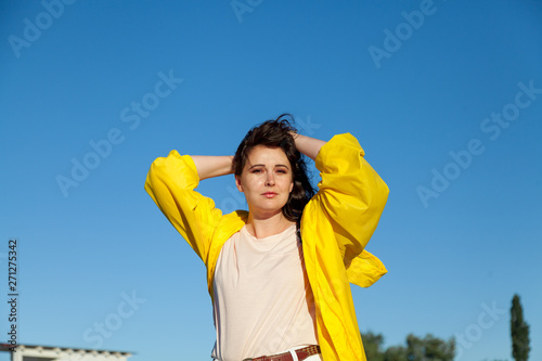 Beautiful plus size woman in yellow jacket against blue sky