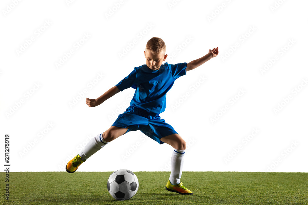 Young boy as a soccer or football player in sportwear making a feint or a kick with the ball for a goal on white studio background. Fit playing boy in action, movement, motion at game.